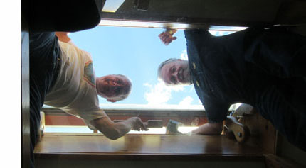 we are looking up at 3 guys standing on a glass platform about 4 feet below the ceiling and looking down at us and smiling.  There is a opening in the ceiling (about 3-4 feet on each side) and they are standing with their heads through the opening and outside.  We can see the sky above them